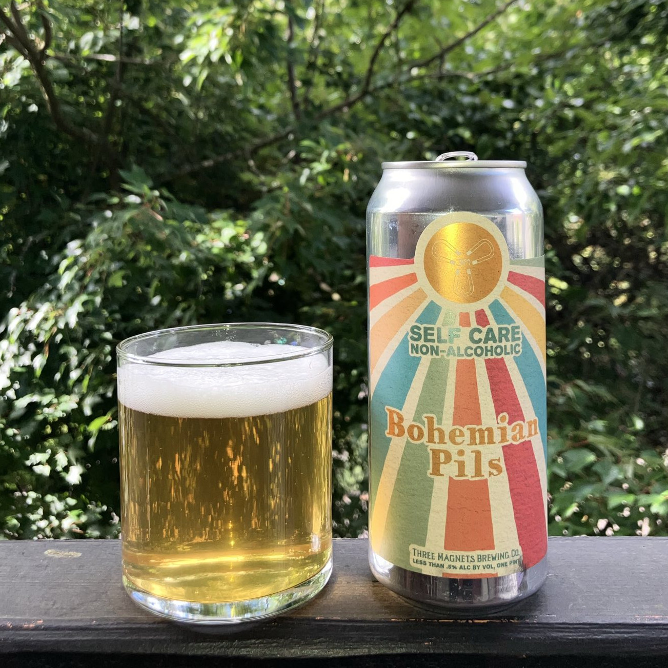 Self-Care Brewing&rsquo;s Bohemian Pils in a pint can, poured into a minimalist lowball glass, on a balcony railing